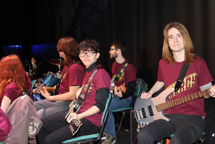 Two young adults holding guitars whilst in rehearsal.