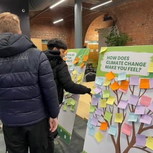 Various students stood by a whiteboard with post-it notes on it.