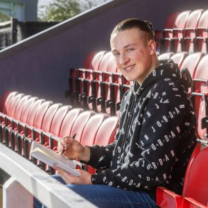 Archie Brown, a former DCG Esports student sat in the stands in a football stadium.