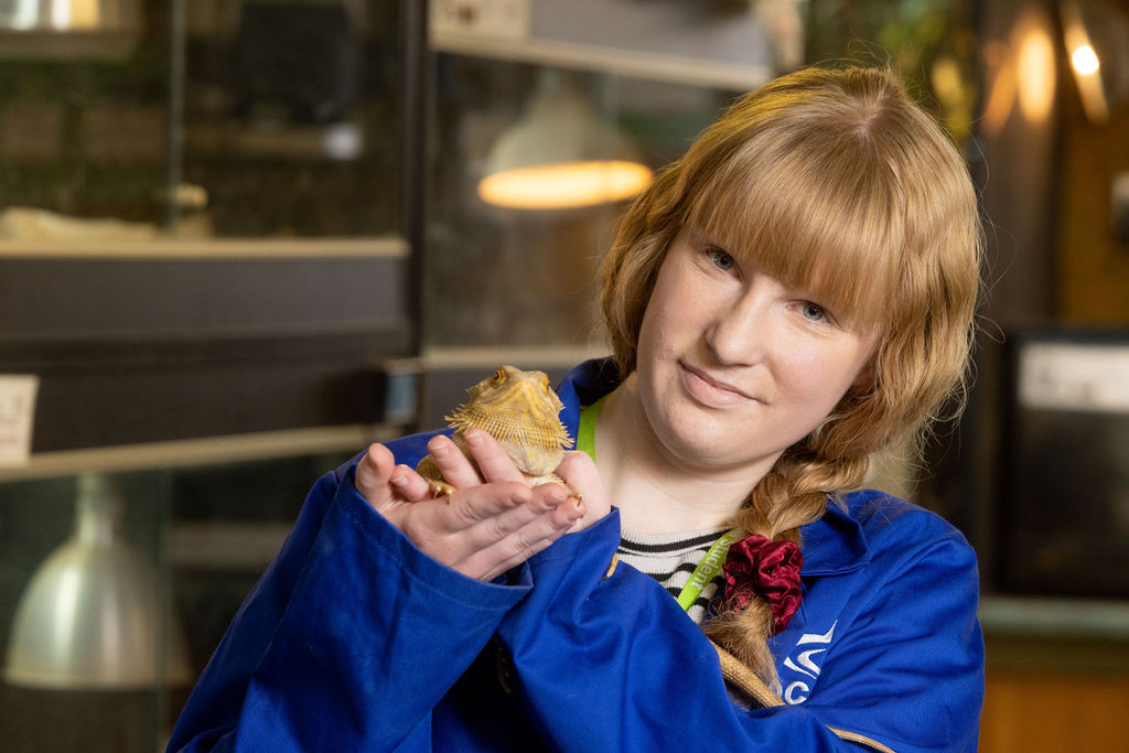 Celine Frosthagen, a student with brown hair wearing a blue coat holding a frog.