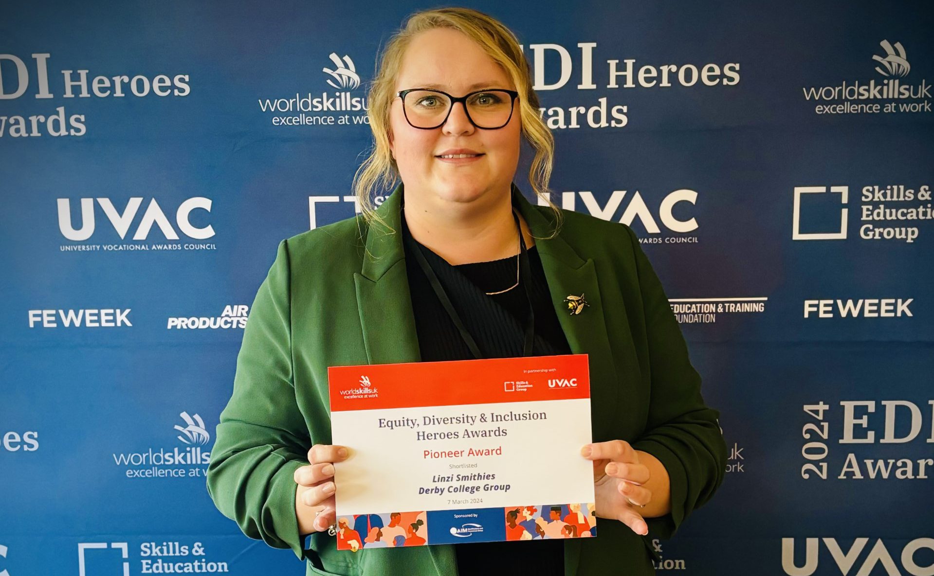 Linzie Smithies, a blinde haired woman wearing a green cardigan holding a certificate