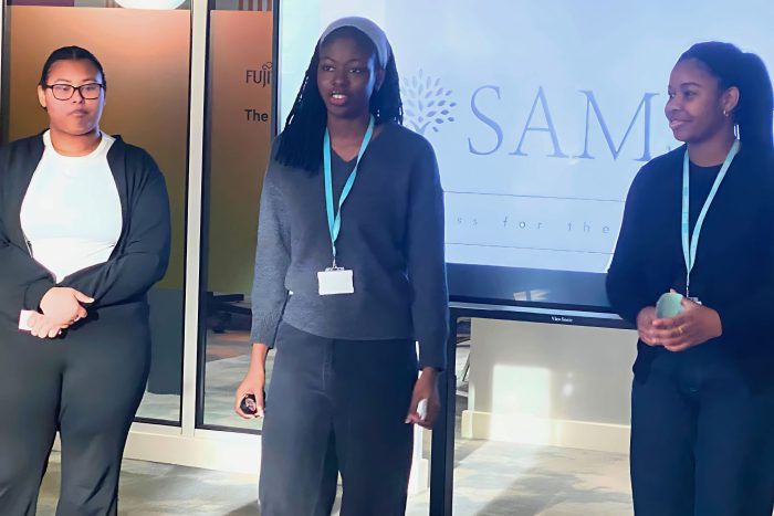 Three students on the winning team delivering their presentation.
