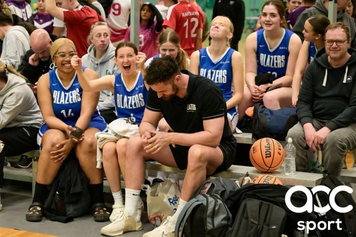 Basketball players watching a team from the sidelines.