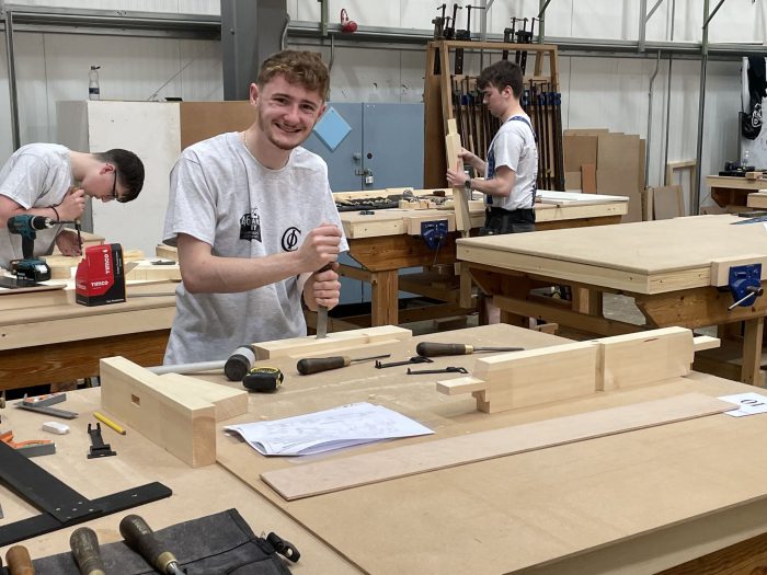 Carpentry apprentice smiling whilst working on a project.