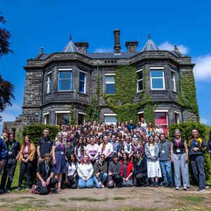A large group of students at a tournament stood outside of a large, old hall