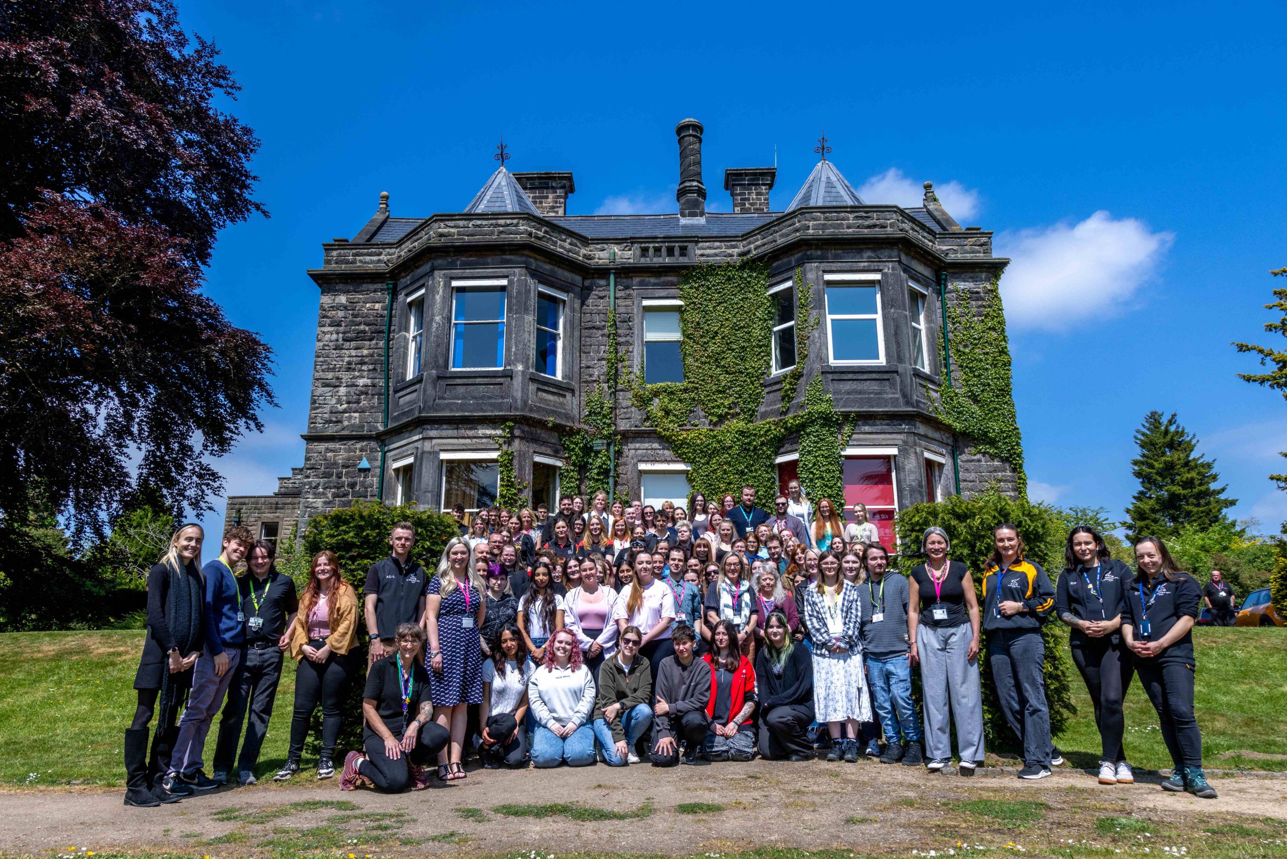 A large group of students at a tournament stood outside of a large, old hall