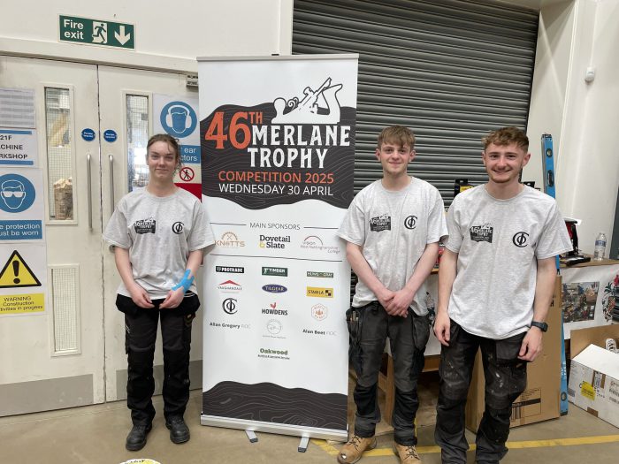 Carpentry apprentices stood by a banner that reads '46 Merlane Trophy'.