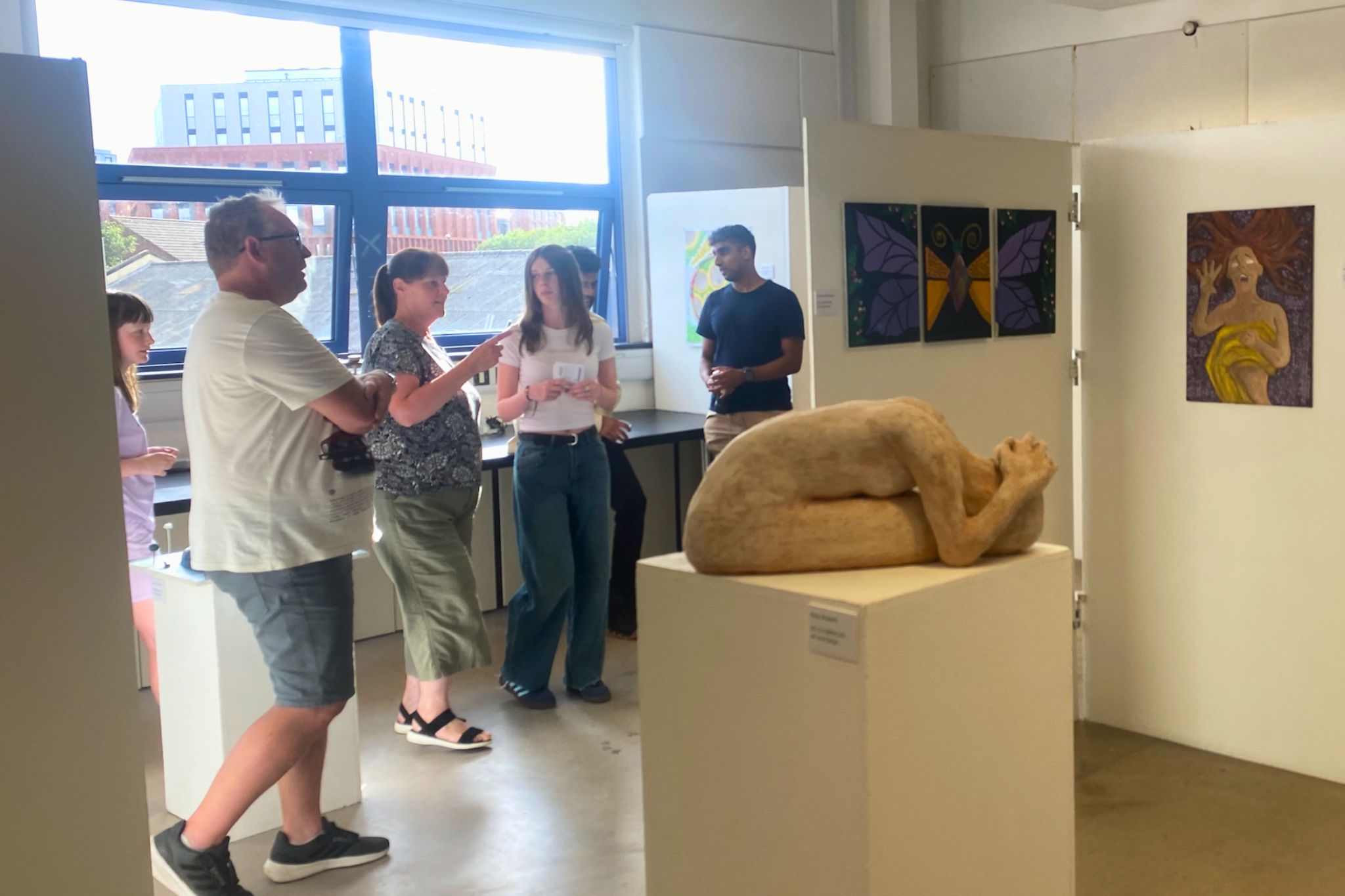 An audience gathered looking at pieces of art at an exhibition.