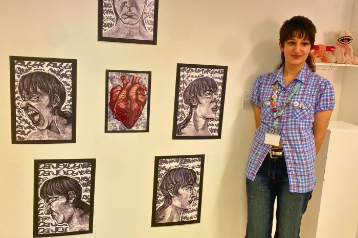 Young student stood by pieces of art they have created.