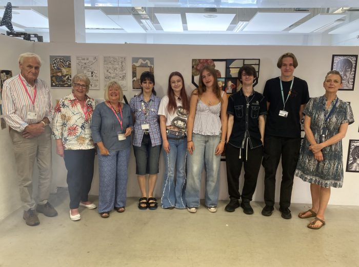 Group of people of mixed genders and ages stood in an art studio.