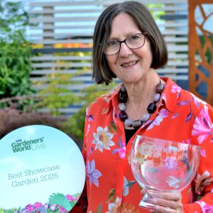 Lady wearing a red floral shirt holding a plate and an award