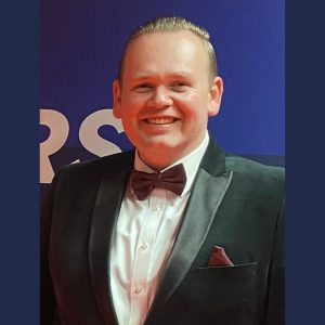 Former Derby College student Ross Sexton wearing a black tuxedo with a burgundy bowtie and pocket tissue.