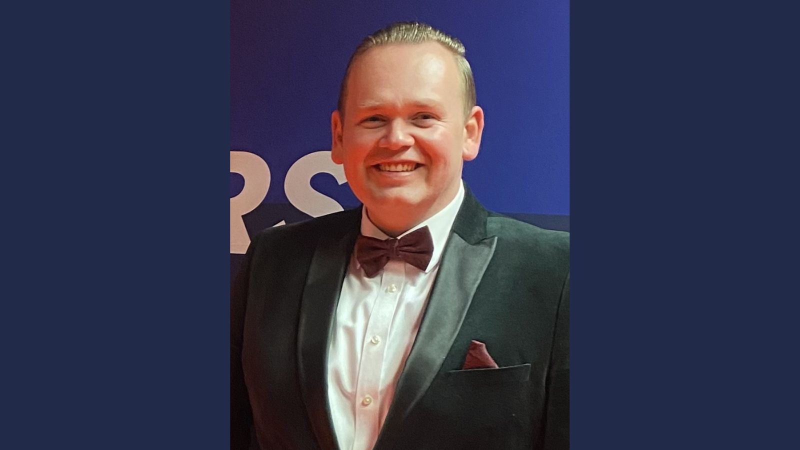 Former Derby College student Ross Sexton wearing a black tuxedo with a burgundy bowtie and pocket tissue.