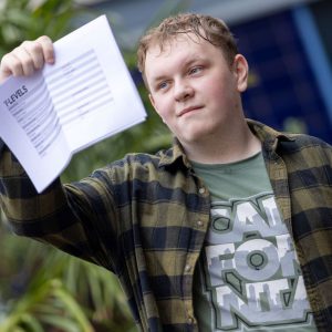 Young student holding their A-level results in the air.