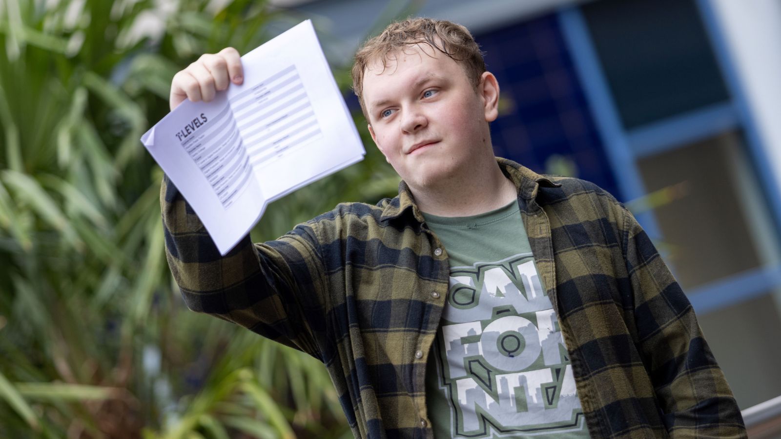 Young student holding their A-level results in the air.