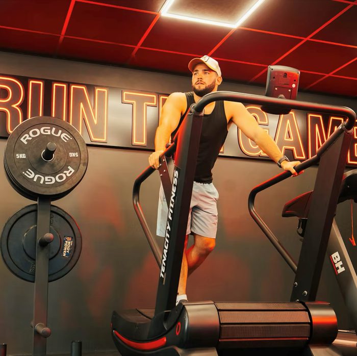 Gym-goer wearing a baseball cap using a treadmill.