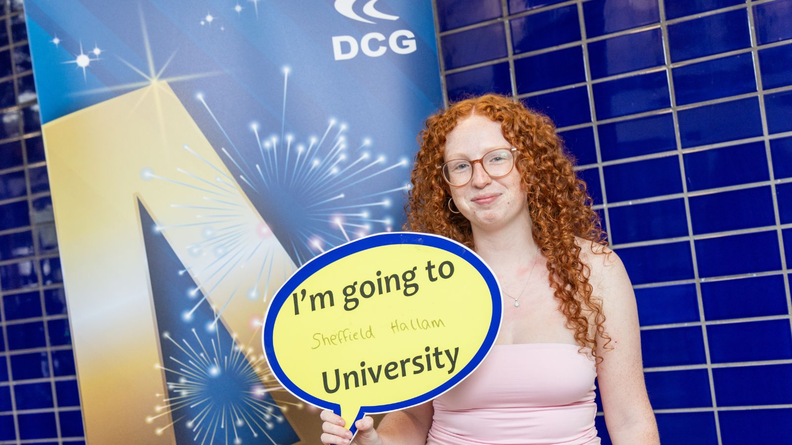 Young student with red, curly hair holding a sign aloft