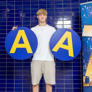 Young students holding two circular signs that read A