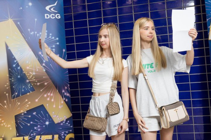Two twins with blonde hair holding certificates