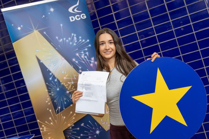 Young student with dark hair holding a card with a star on it.