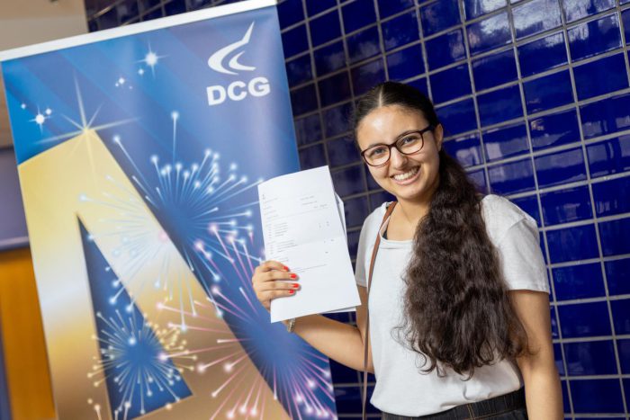 Young student wearing glasses holding their results on A-level results day
