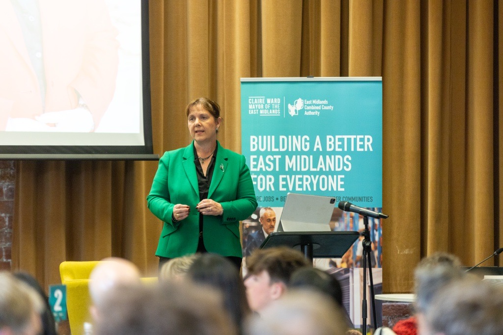 Mayor Claire Ward wearing a green blazer, speaking to a room a people.
