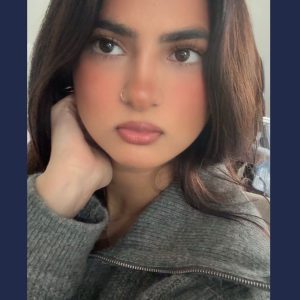 Person wearing a grey zip-up sweater inside with soft furnishings visible in the background.