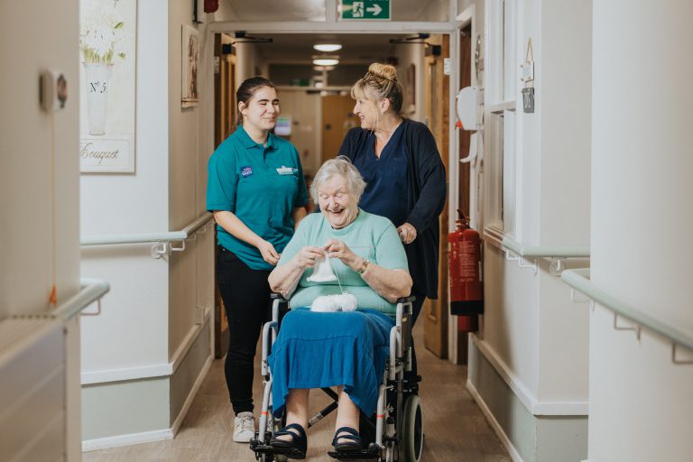 Student and care worker pushing an elderly woman in her wheelchair