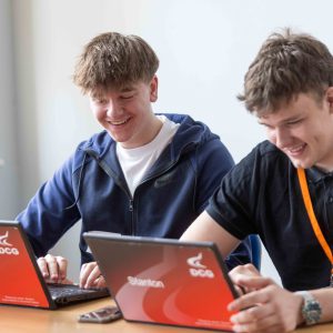 Two students using a laptop, studying a Business course at Derby College Group