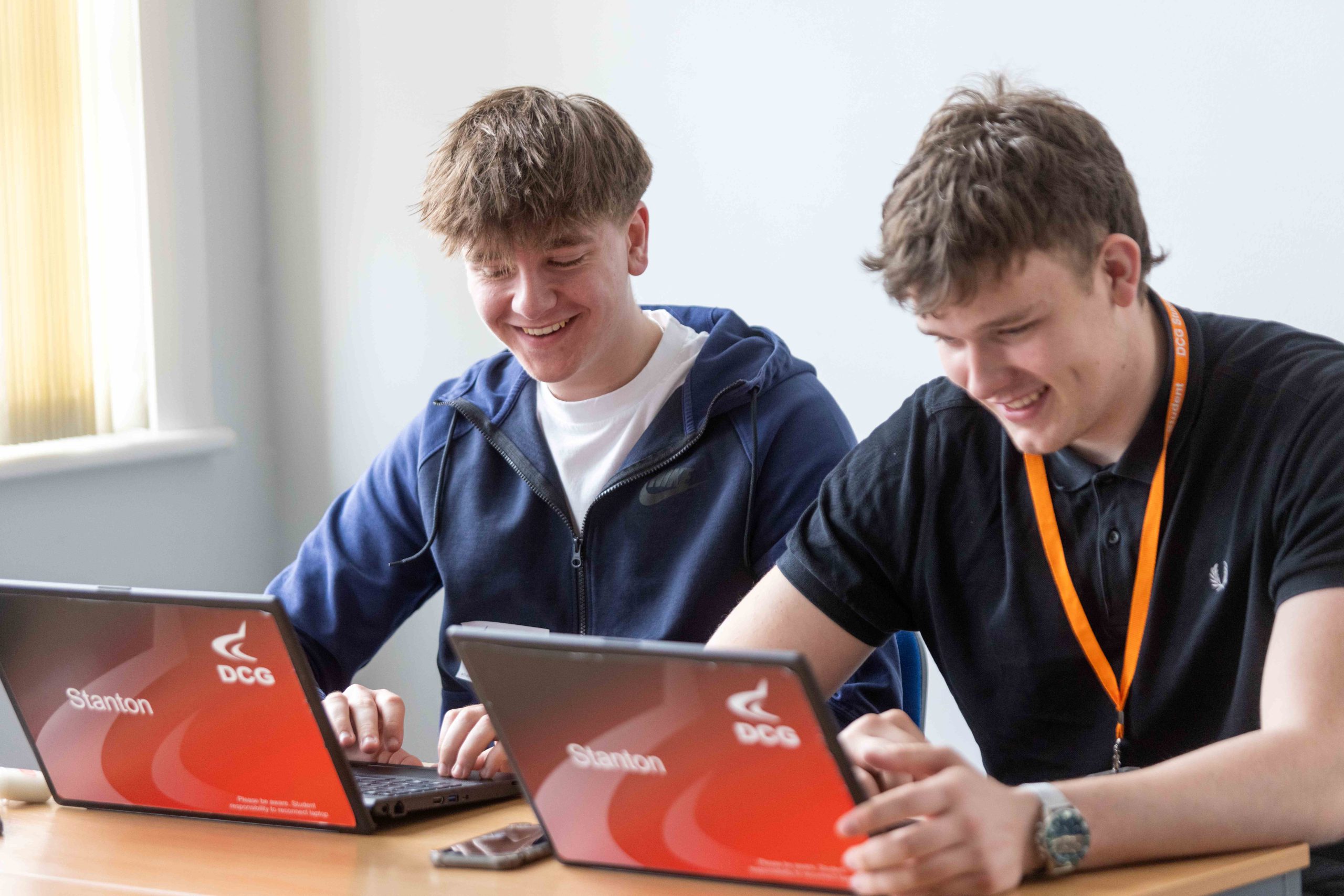 Two students using a laptop, studying a Business course at Derby College Group