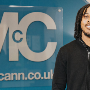 FP McCann logo and website displayed on a blue wall inside an office reception area, promoting engineering courses and services in civil engineering and construction.