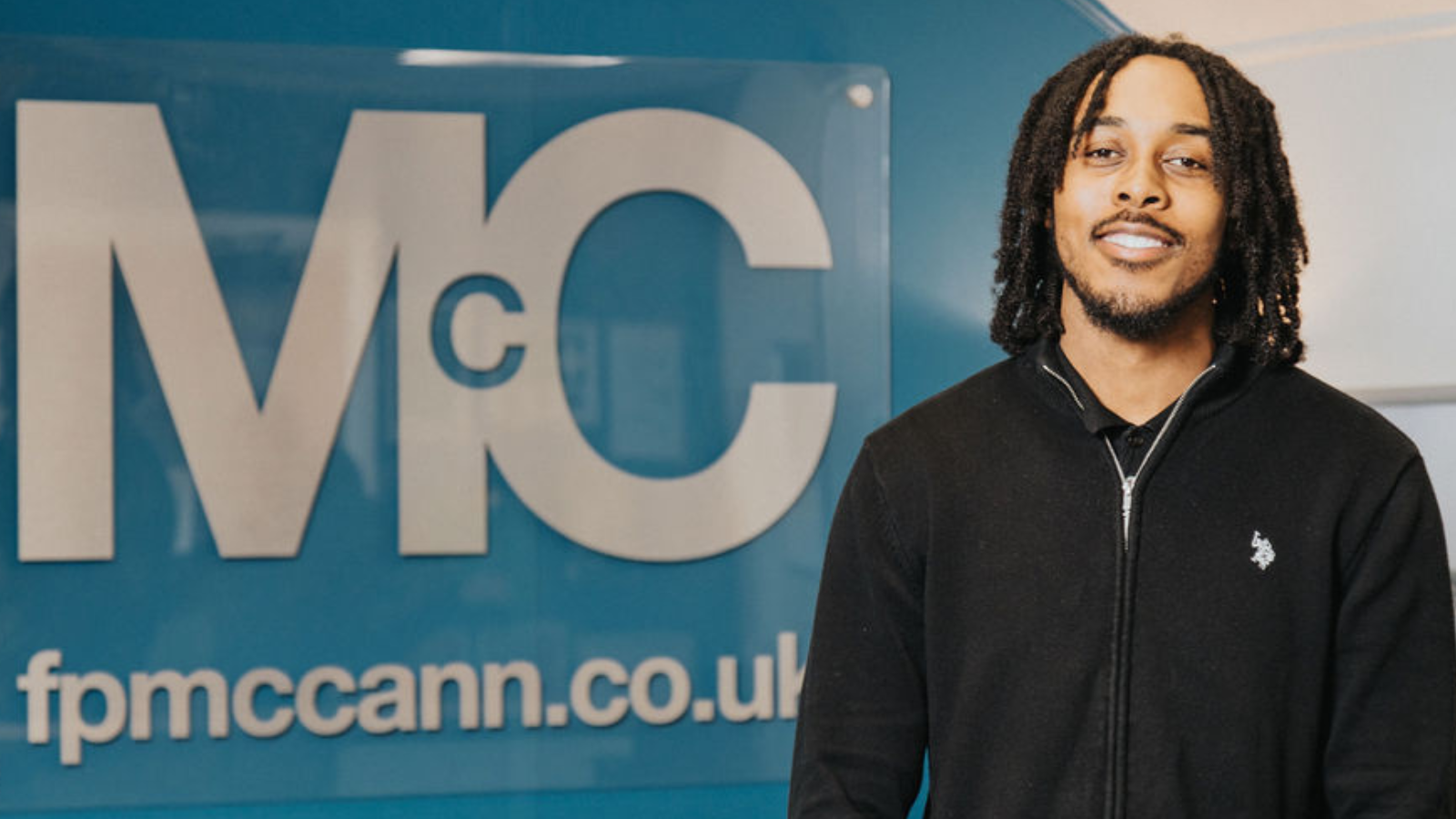 FP McCann logo and website displayed on a blue wall inside an office reception area, promoting engineering courses and services in civil engineering and construction.