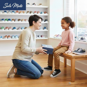 Person and a child trying shoes on at a shoe store.