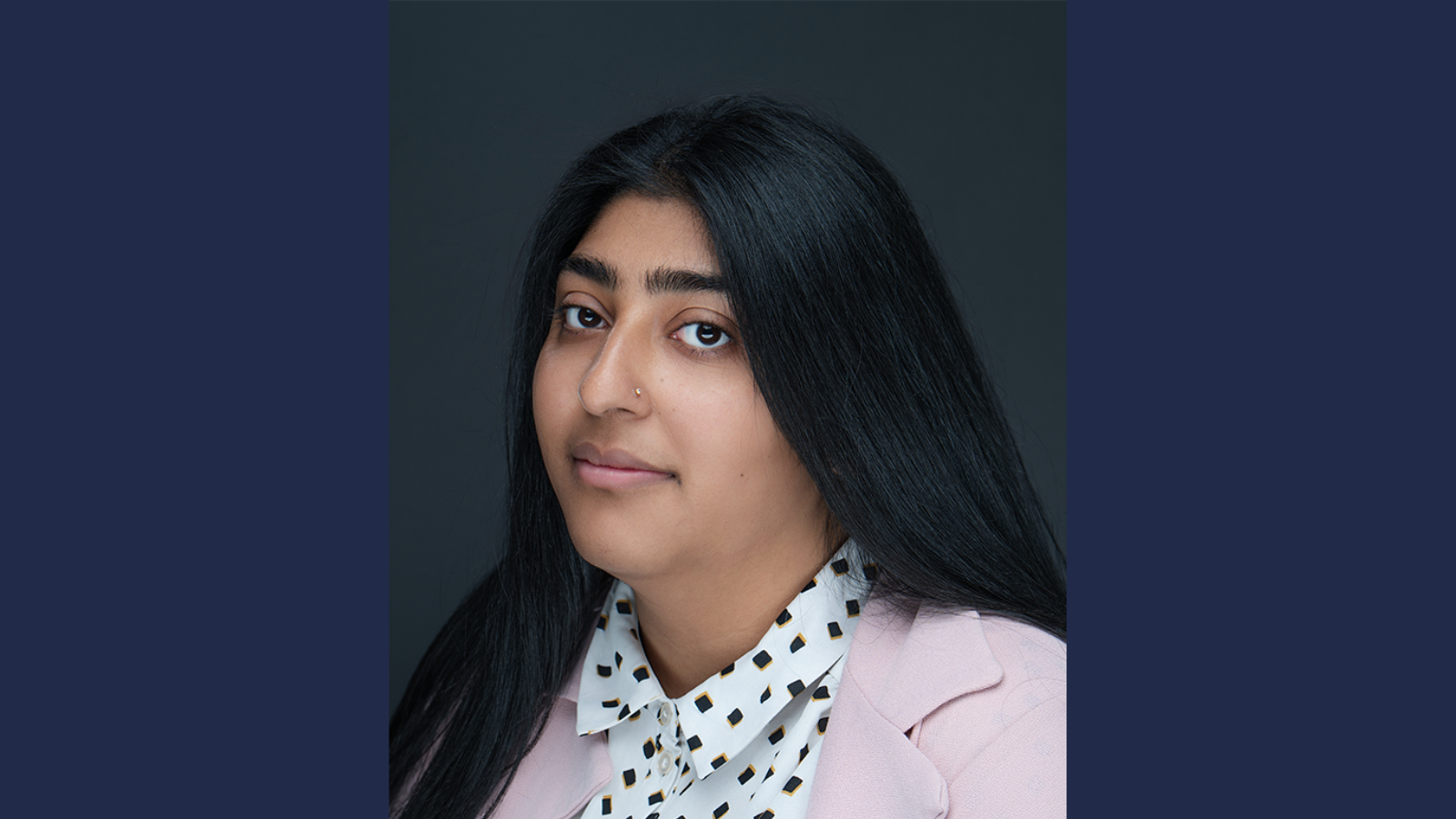 Young person with dark hair and a white shirt with a pattern.