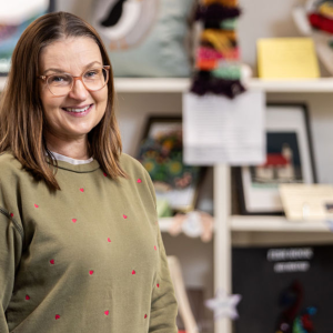 Adult learning and upcycling student Kathryn stood in-front of a big display of crafted items.