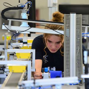 Apprenticeship student with red hair working on a piece of machinery in an Engineering setting.