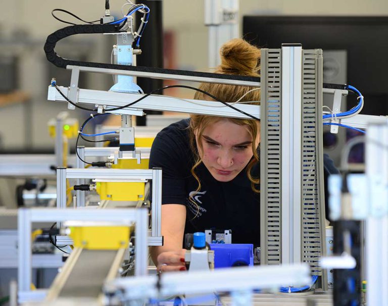 Apprenticeship student with red hair working on a piece of machinery in an Engineering setting.
