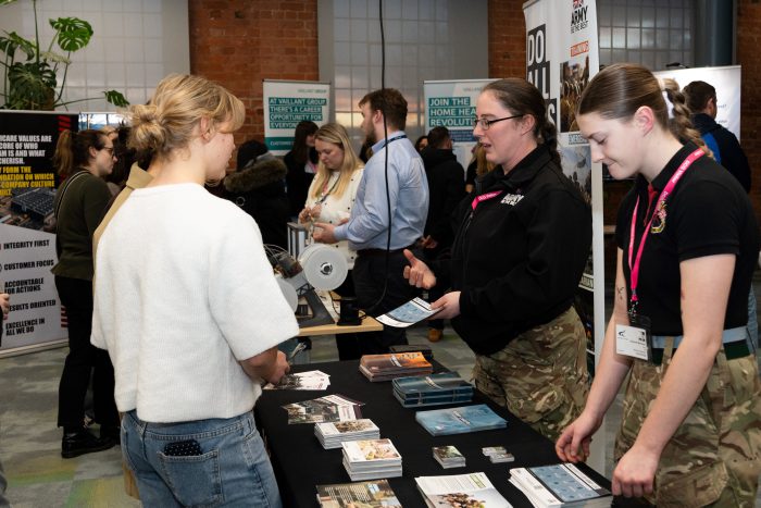 Attendees visit an exhibitor table at a STEM and engineering event, where representatives share information about engineering career pathways and opportunities.