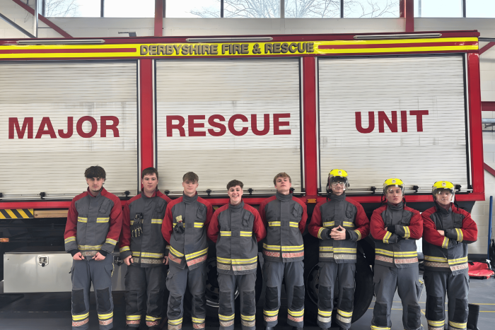 Group of Derby College Public Services students in firefighter gear standing in front of the Derbyshire Fire & Rescue Service Major Rescue Unit during a firefighter experience day.