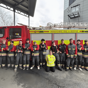 Derby College Public Services students standing in front of a Derbyshire Fire & Rescue Service fire engine during their firefighter experience day.