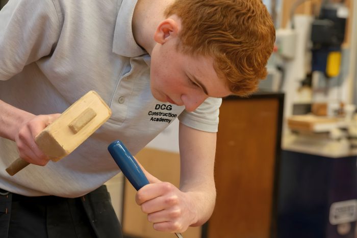 Student working on a carpentry project in a college workshop, using woodworking tools during the SkillsFest competition at a Derby, Chesterfield and Burton colleges event.