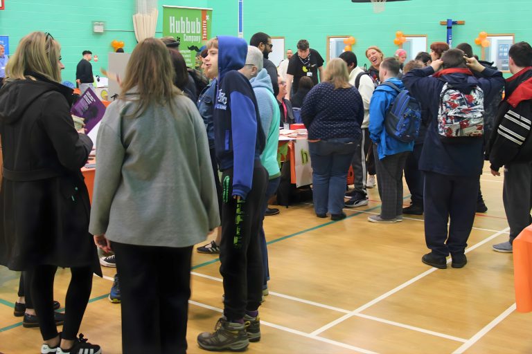 Attendees gather around exhibitor stalls inside the Inclusion Showcase 2026 venue, engaging in conversations and exploring opportunities from community organisations.