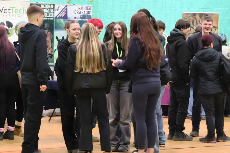 Group of students gathered in a sports hall, speaking with employers and exploring stands related to land‑based and animal care careers.