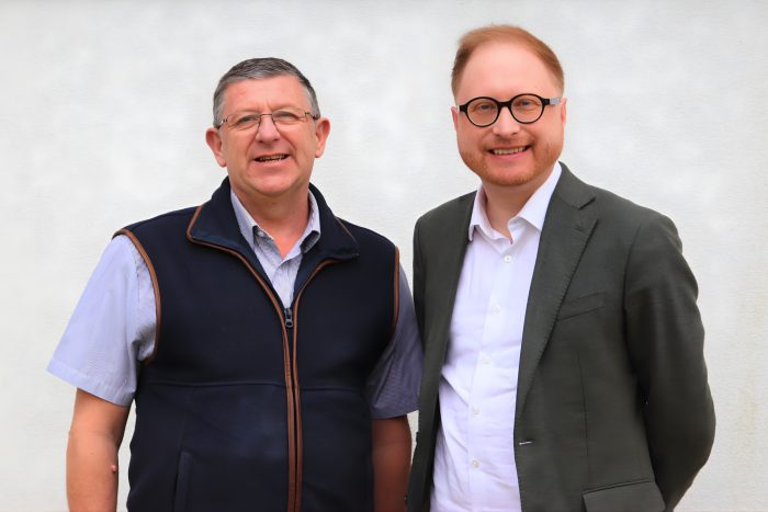 Two people, Jonathan Davies and Jon Collins stood in front of a white background.