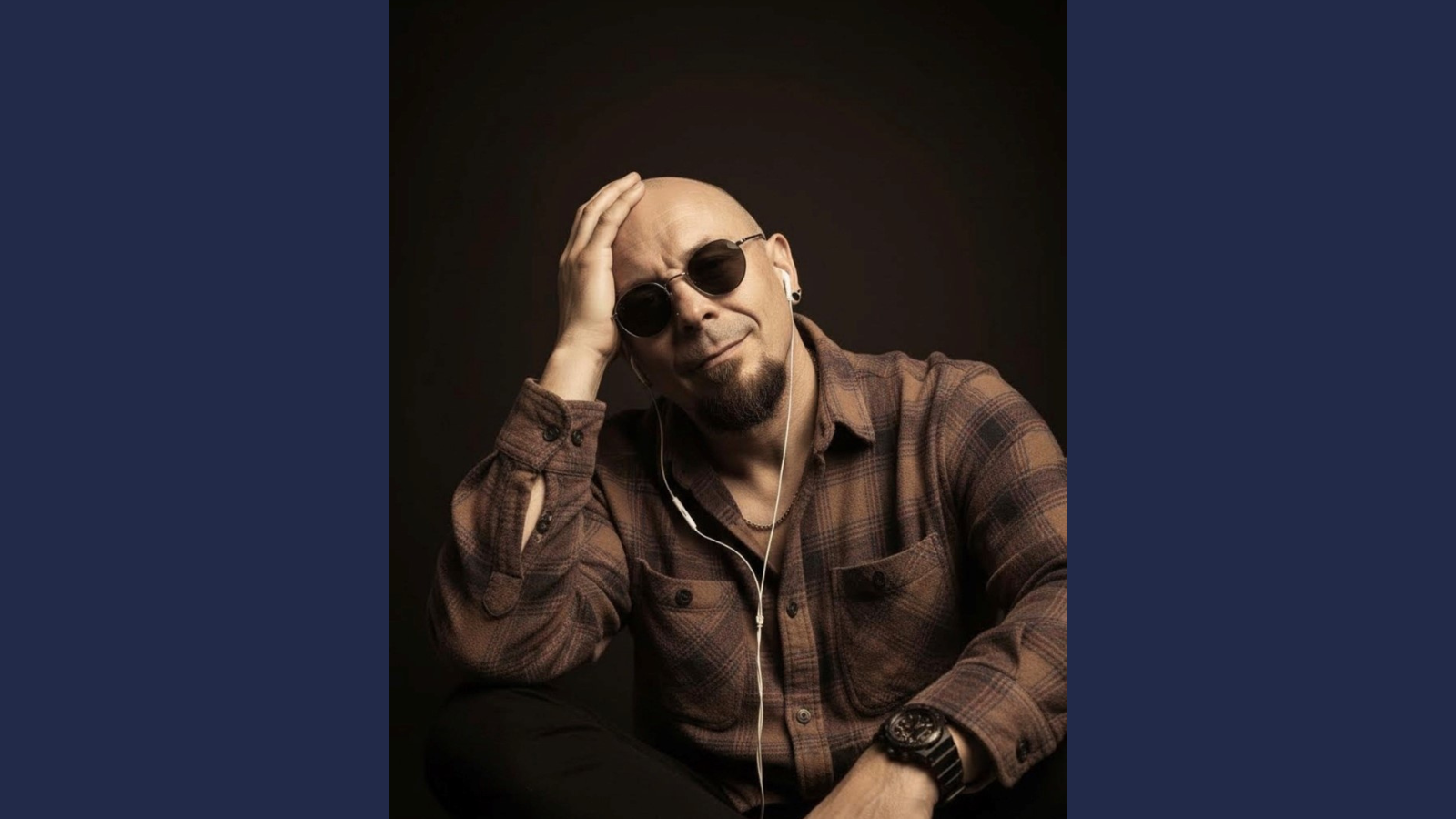 Derby College Distance learning student wearing a checked shirt and sunglasses against a dark background.