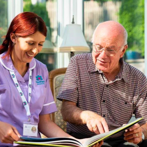 Elderly person reading a book with a carer from Radfield Home Care