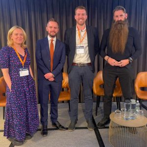 Panel speakers standing on stage during an education and technology discussion at the Training and Technology Summit in London.