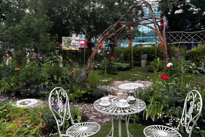 The Artist’s Garden show garden at BBC Gardeners’ World Live featuring cottage-style planting, metal seating set, willow arch and landscaping created by Derby College horticulture students