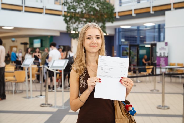 A-level student Gracie Ryan holding a paper with her results on.