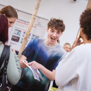 Young people holding pieces of paper with their Level 3 results on them.